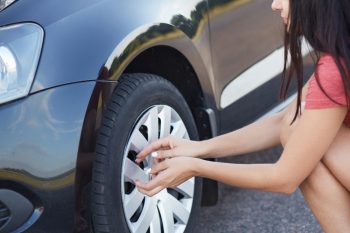 Mujer revisando las llantas de su camioneta suv